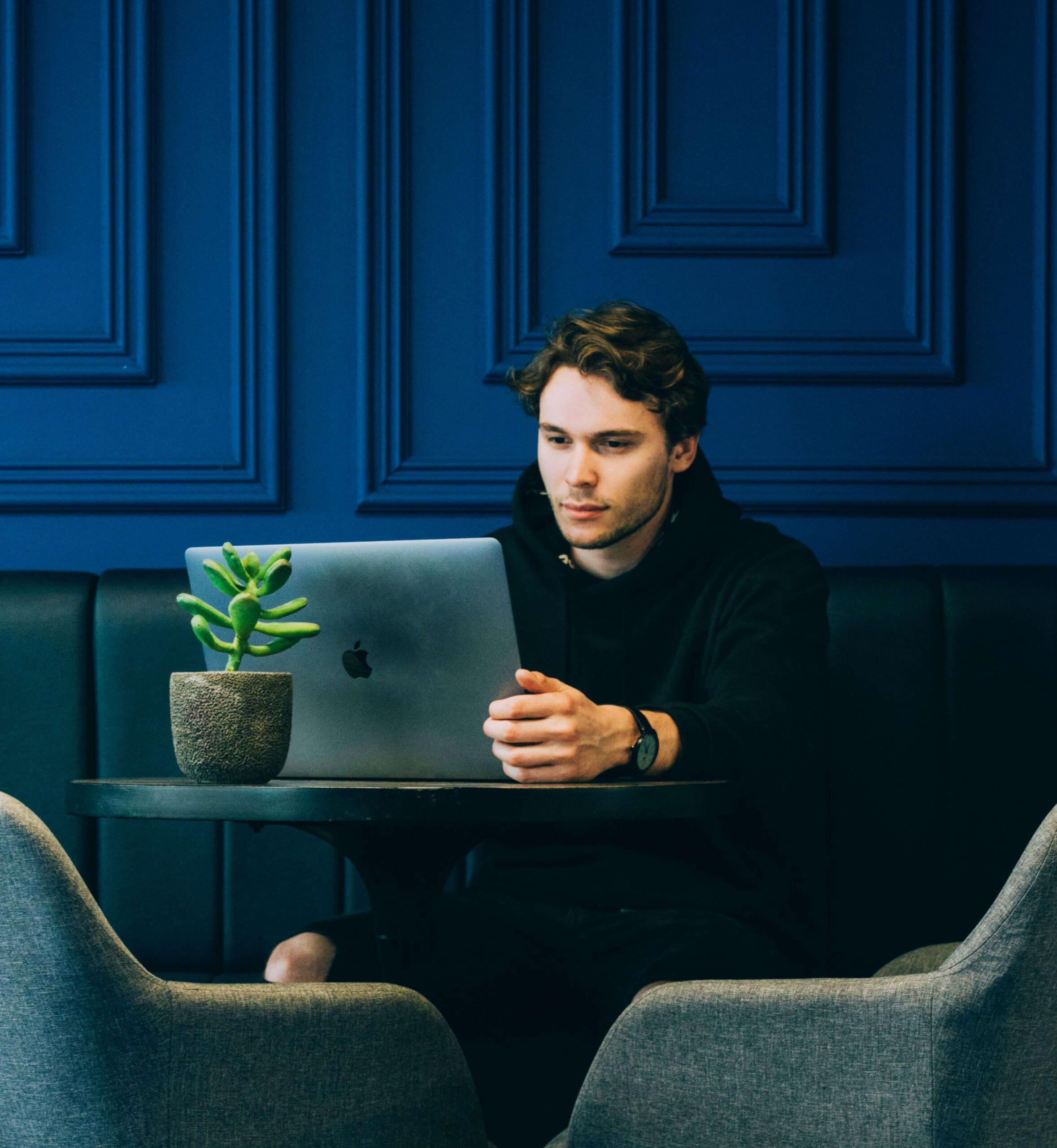 Young man behind a laptop, working.