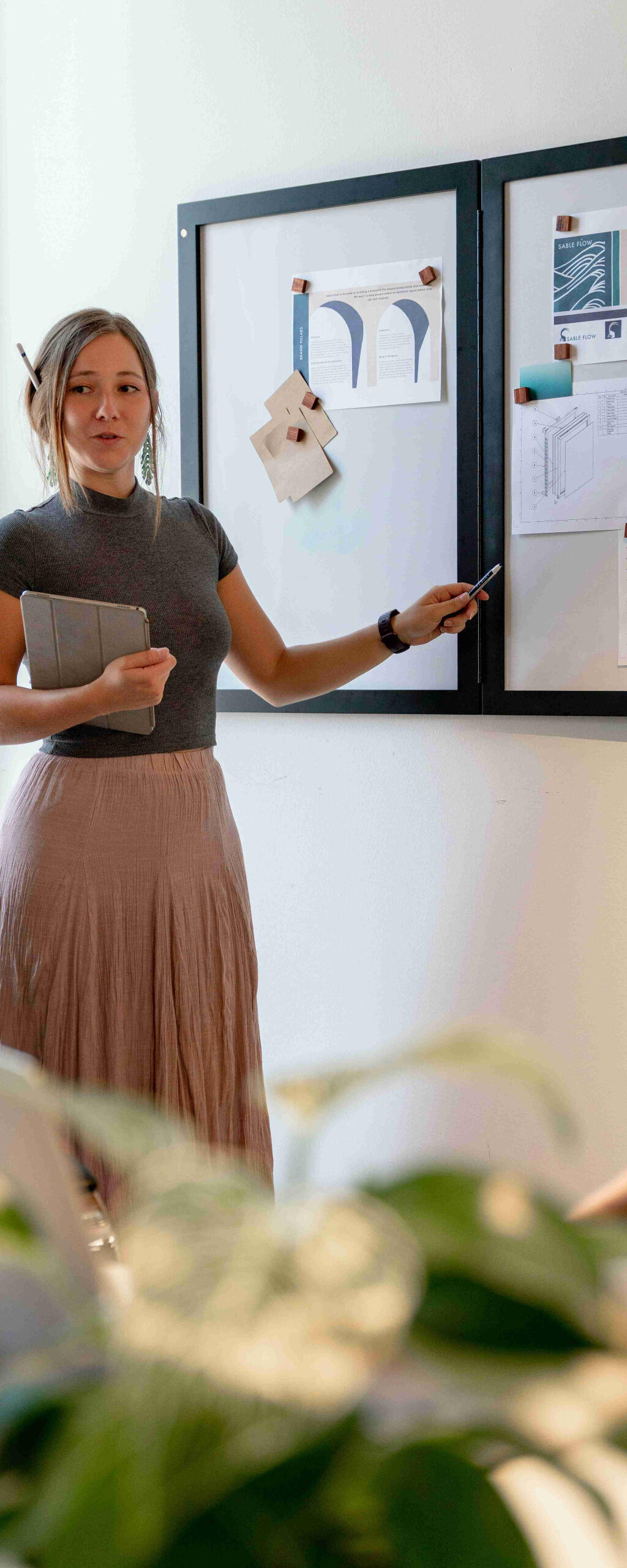 Young woman giving a presentation in front of a series of whiteboards.